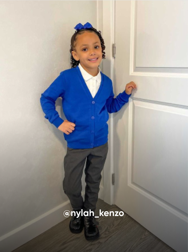 girl posting and smiling by a door - Visit Kickers Kids Instagram